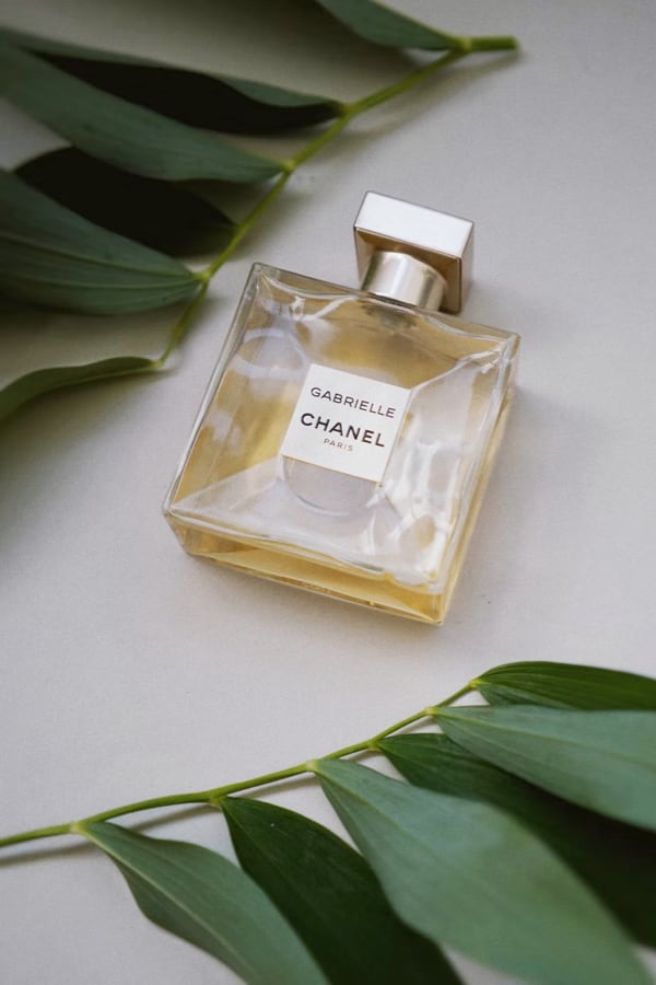 Image of a perfume bottle on a white background with leaves